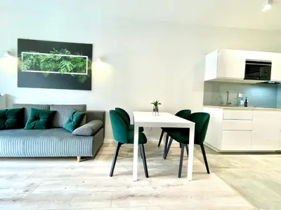 a living room with a table and chairs and a couch at Modern Green Apartment in Kraków
