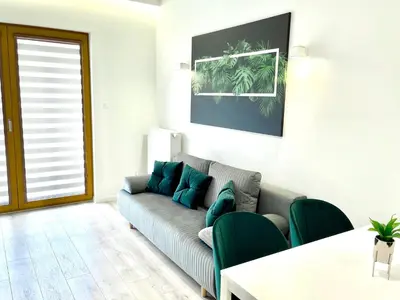 a living room with a couch and green chairs at Modern Green Apartment in Kraków