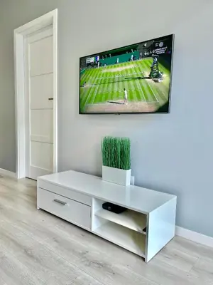 a white living room with a tv on a wall at Modern Green Apartment in Kraków