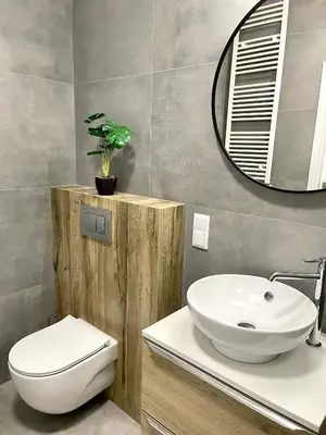 a bathroom with a sink and a toilet and a mirror at Modern Green Apartment in Kraków