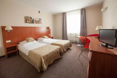 a hotel room with two beds and a desk and a television at H6 MAJOR ApartHotel Travel & Business, FREE PARKING in Kraków
