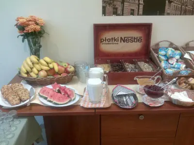 a table with plates of food and a basket of fruit at H6 MAJOR ApartHotel Travel & Business, FREE PARKING in Kraków