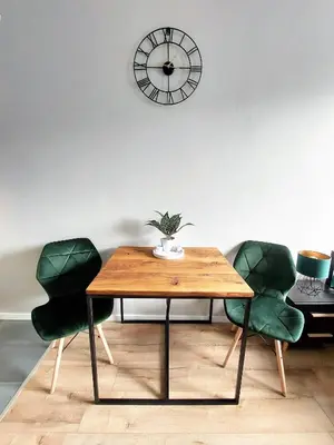 a table with green chairs and a clock on the wall at Krakowska Awangarda - Close to the Old Town in Kraków