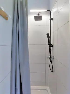 a shower with a blue shower curtain in a bathroom at Krakowska Awangarda - Close to the Old Town in Kraków