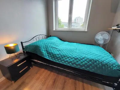 a bedroom with a bed with a green comforter and a window at Krakowska Awangarda - Close to the Old Town in Kraków