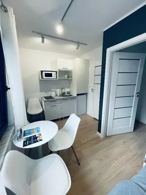 a room with a table and chairs and a kitchen at Beds Friends Apartments in Zator