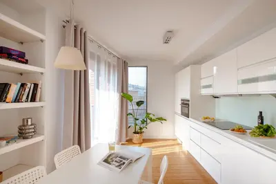 a white kitchen with a table and chairs and a window at Spacious apartment close to Main Station / Galeria Krakowska in Kraków