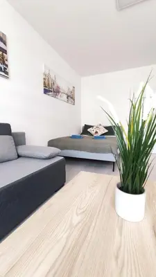 a living room with two beds and a potted plant at Dąbska 18D by Homeprime in Kraków