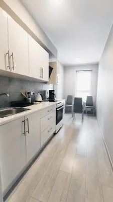 a kitchen with white cabinets and a wooden floor at Dąbska 18D by Homeprime in Kraków