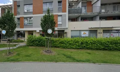 two trees in the grass in front of a building at Dąbska 18D by Homeprime in Kraków