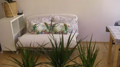 a white chair with two pillows and a plant at New Sweet One in Kraków