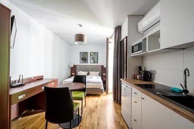 a kitchen with a table and a room with a bed at ON/SET APARTHOTEL in Kraków