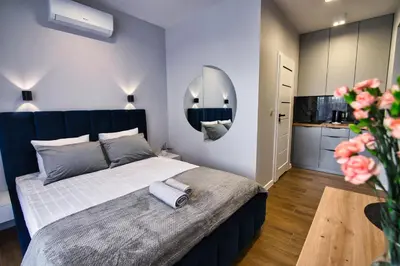 a bedroom with a large bed and a kitchen at Apartament dla dwojga in Zator