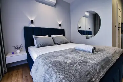 a bedroom with a bed with a blue headboard and a mirror at Apartament dla dwojga in Zator