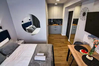 a bedroom with a bed and a table and a kitchen at Apartament dla dwojga in Zator