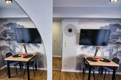 two tables with chairs and a tv on a wall at Apartament dla dwojga in Zator