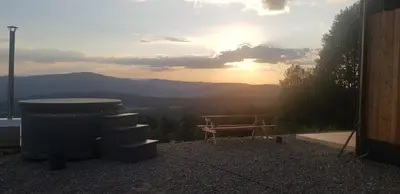 a hot tub and a picnic table with the sunset in the background at Reset Kudłacze in Pcim