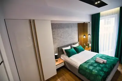a bedroom with a large bed with green pillows at Capital apartaments in Zator
