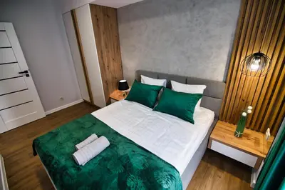 a bedroom with a large bed with green pillows at Capital apartaments in Zator