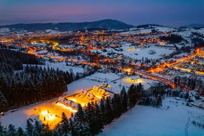 a view of a town in the snow at night at Kompleks Gazdówka - Domki Rabka-Zdrój in Ponice