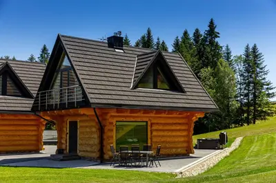 a log cabin with a black roof at Kompleks Gazdówka - Domki Rabka-Zdrój in Ponice