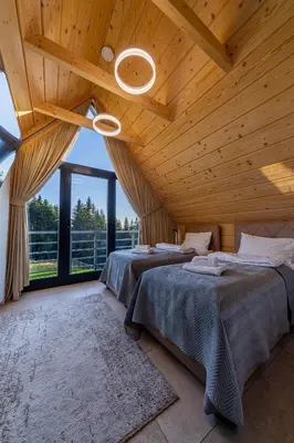 two beds in a room with a wooden ceiling at Kompleks Gazdówka - Domki Rabka-Zdrój in Ponice