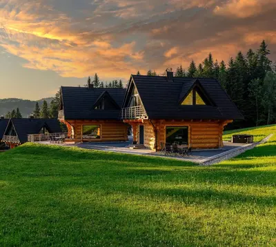 a log cabin on a hill with green grass at Kompleks Gazdówka - Domki Rabka-Zdrój in Ponice