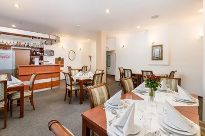 a restaurant with tables and chairs and a bar at Hotel Artur in Kraków