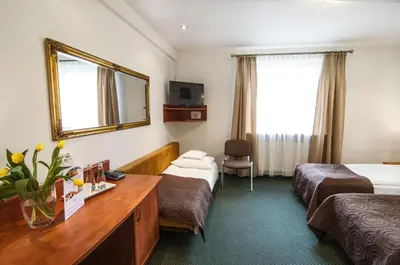 a hotel room with two beds and a mirror at Hotel Artur in Kraków