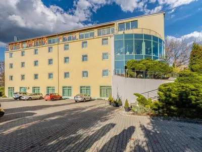 a large yellow building with cars parked in a parking lot at Hotel Artur in Kraków
