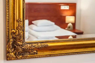 a gold mirror on a table with a bed at Hotel Artur in Kraków