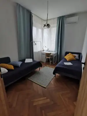 a room with two beds and a table with a window at Apartament z klimatyzacją in Kraków