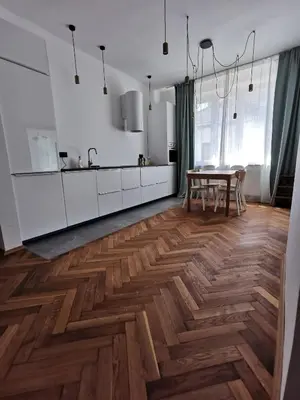 a kitchen with white cabinets and a wooden floor at Apartament z klimatyzacją in Kraków