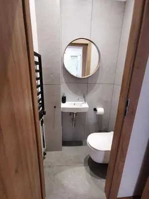 a bathroom with a white toilet and a mirror at Apartament z klimatyzacją in Kraków