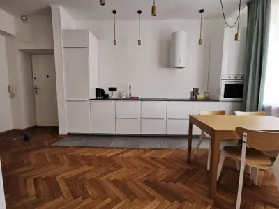 a kitchen with white cabinets and a wooden table at Apartament z klimatyzacją in Kraków