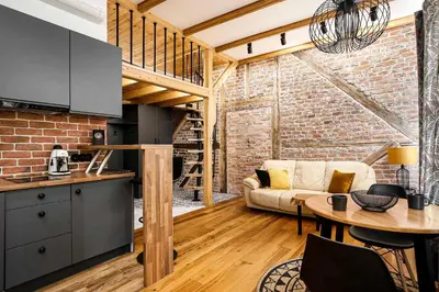 a kitchen and living room with a brick wall at Charming Studio with Air Conditioning, Old Town & Kazimierz in Kraków