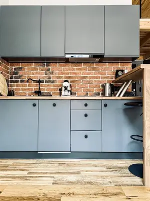 a kitchen with white cabinets and a brick wall at Charming Studio with Air Conditioning, Old Town & Kazimierz in Kraków