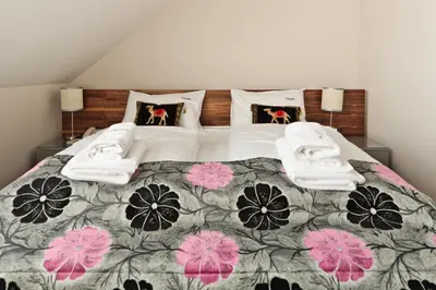a bedroom with a large bed with pink flowers on it at Jasmin Complex Resort & Spa in Krzeszów Dolny