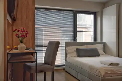 a bedroom with a bed and a table and a chair at Aparts Near Main Station in Kraków