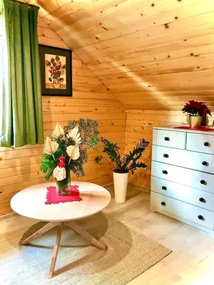 a room with a table with flowers and a dresser at Domek w borówkach in Tokarnia