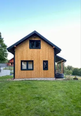 a wooden house with two windows on a grass field at Domek w borówkach in Tokarnia