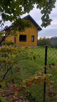 a fence in front of a house with a building at Domek w borówkach in Tokarnia
