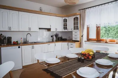 a kitchen with white cabinets and a table and chairs at Dom Marika - Energylandia Zator in Zator