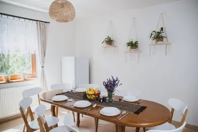 a dining room with a wooden table and white chairs at Dom Marika - Energylandia Zator in Zator