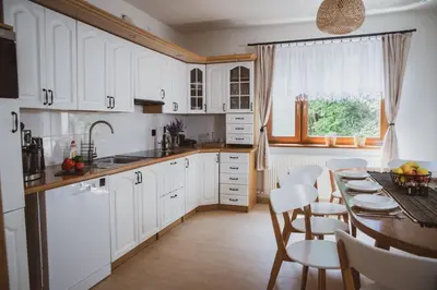 a kitchen with white cabinets and a table and chairs at Dom Marika - Energylandia Zator in Zator