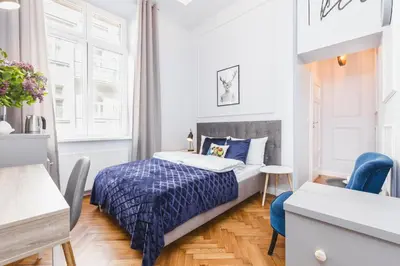 a small bedroom with a bed and a blue chair at Traveler's Best Choice - Old Town Guesthouse - by Upstairs in Kraków