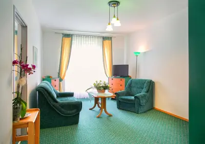 a living room with two chairs and a table and a tv at Hotel Monttis in Sucha Beskidzka
