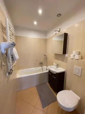 a bathroom with a toilet and a tub and a sink at Apartamenty Przy Parku in Rabka