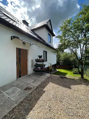 a white house with a tree in the yard at Apartament Ptasi Śpiew in Rabka