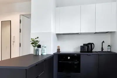 a kitchen with white cabinets and a black counter top at PLANTONIA Aparthotel in Kraków